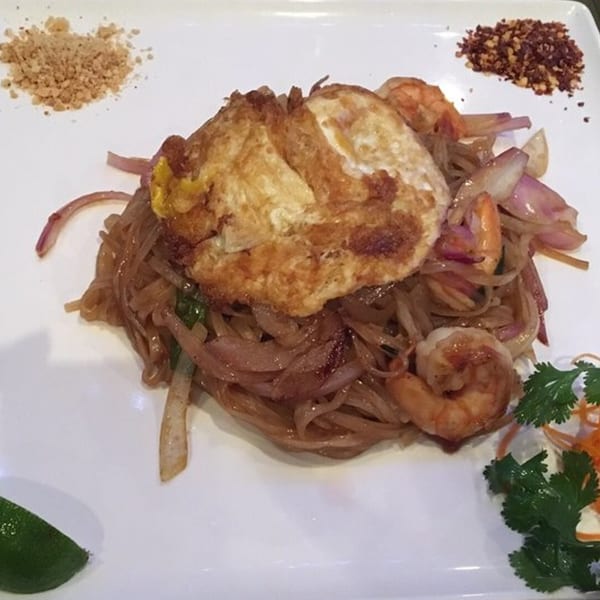 Pad Thai with shrimp, fried egg, red onions, and lime on a white plate at Osaki Japanese Cuisine.