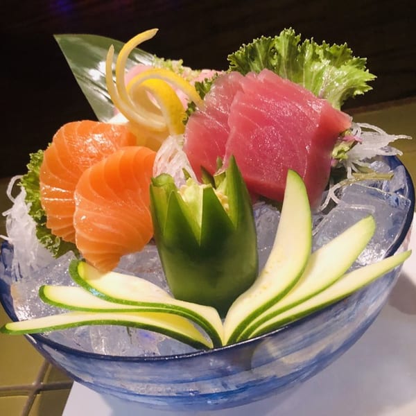 Osaki Japanese Cuisine's sashimi platter with salmon, tuna, and decorative vegetables on ice in a blue bowl.